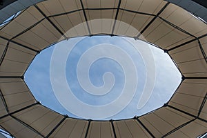 a small circular skylight at an airport lobby with clouds in the background