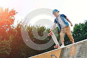 A small city boy and a skateboard. A young guy is riding in a park on a skateboard. City Style. City children. A child learns to