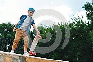 A small city boy and a skateboard. A young guy is riding in a park on a skateboard. City Style. City children. A child learns to