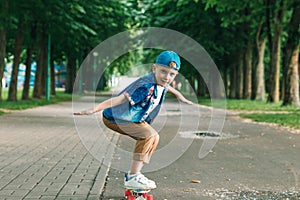 A small city boy and a skateboard. A young guy is riding in a park on a skateboard. City Style. City children. A child learns to