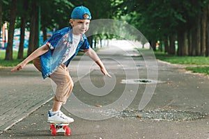 A small city boy and a skateboard. A young guy is riding in a park on a skateboard. City Style. City children. A child learns to