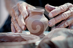 Small clay vase and hands of working potter