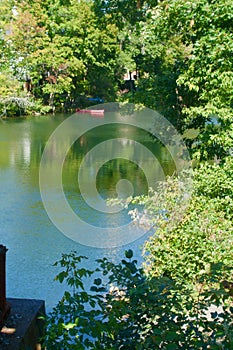 Small clean river with trees reflected and red canoe parked on bank