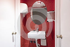 Small cloakroom with oval bevelled mirror, red tiles and small white porcelain sink