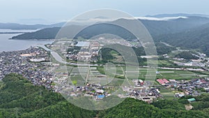 Small coastal town and rice fields with mountains and fog in background