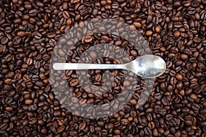 Background with many coffee beans and metal spoon photo