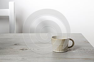 Small coffee cup is on a beige table. Place for text