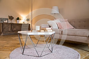 Small coffee table and candles next to designed sofa with pastel colored pillows.Still life details of nordic living