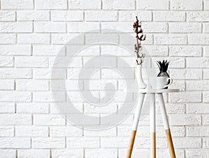 Small coffee table with cup and decor on the white brick wall ba