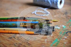 Small collection of artist brushes and twine in a studio setting.