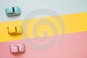 Small color toy cars at the start on a yellow, pink and blue background. Racing cars on a table top racetrack