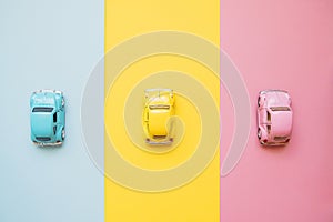 Small color toy cars on a yellow, pink and blue background. Business competition, winners and losers. Finish line
