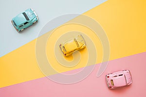 Small color toy cars on a yellow, pink and blue background. Business competition, winners and losers. Finish line