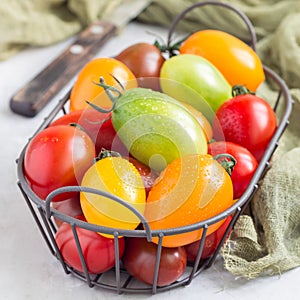 Small colorful cherry tomatoes in metal basket, square format