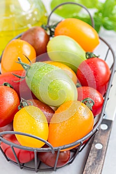 Small colorful cherry tomatoes in metal basket, vertical