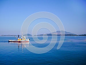 Small colorful fishing boat in calm water with blue sky