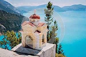 Small colorful Hellenic shrine Proskinitari near edge cliff. Amazing sea view to coastline in the background