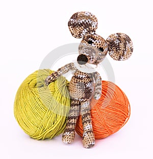 Small colorful knitted toy mouse in a white scarf playing with c