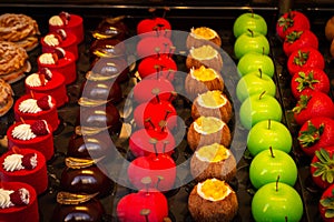 Small colorfull cakes with different stuffing on a showcase in shop