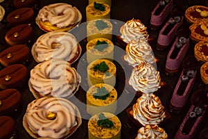 Small colorfull cakes with different stuffing on a showcase in shop