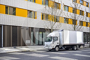 Small compact cab over truck with box trailer delivering cargo to multilevel urban city apartments