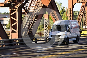 Small compact cargo mini van driving on the truss bridge