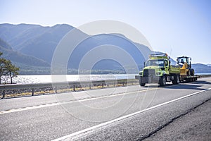 Small compact semi tip truck transporting multifunctional tractor driving on the road along Columbia River