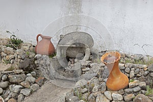 A small concrete frog sculpture in a dry fount with two red ceramic pots photo