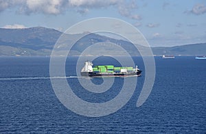 Small container ship sailing near sea coast close to Gibraltar.