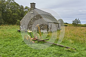 A small Cottage with an Antique Horse Drawn Hay cutter parked outside it, at Crombie Park near Dundee.