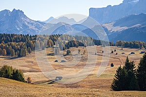 Small cottage in vast and beautiful autumn landscape with mountains and woods, Dolomites, Italy