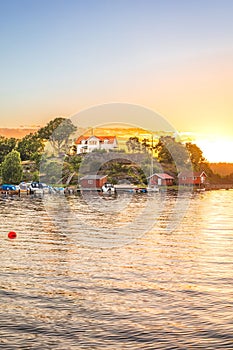 Small cottages with boats in the river at sunset in Henan, Orust, Sweden.