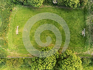 Small country football grass field surrounded by trees, aerial view