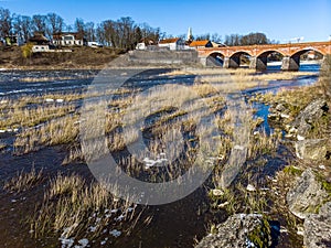 Small countryside city in Kurzeme view of river Venta flowing towards old brick bridge photo