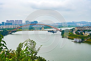 Small county town buildings and rainbow bridge across the river in Guangxi, China
