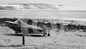 Small covered fishing boat on quiet beach (black and white)