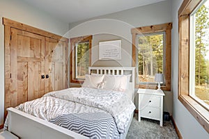 Small yet cozy bedroom interior features white bed with headboard