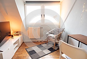 Small cozy living room with hardwood floors, a TV and an armchair in a reading corner