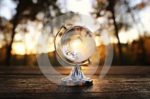 small crystal globe in front of sunset. travel and global issues concept