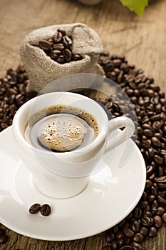 Small cup of black coffee with coffee beans