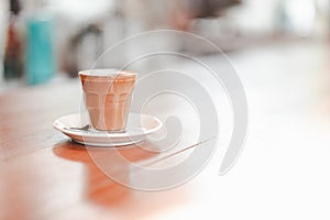 Small cup of piccolo latte served on wooden table with copy space on right