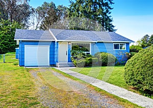 Small cute blue house with driveway and trimmed hedges.