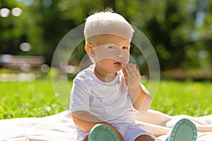 Small cute boy eating sweets in the park