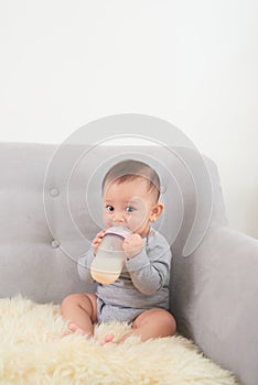 Small cute girl drink milk while lying on blue sofa at home