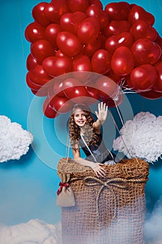 Small cute girl flying on red heart balloons Valentines day