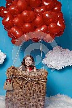 Small cute girl flying on red heart balloons Valentines day