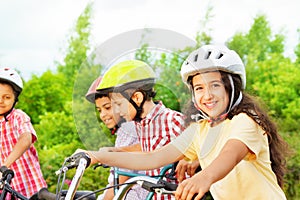 Small cute girl in helmet holds bike handle-bar