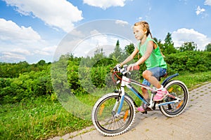 Small cute girl riding children bike on road photo