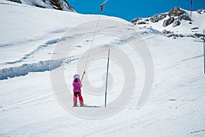 Small cute girl taking a ski lift and learning to ski on a sunny day.