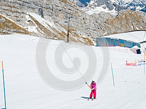 Small cute girl taking a ski lift and learning to ski on a sunny day.